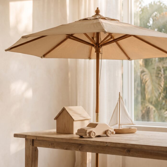 A large open umbrella sheltering a small wooden model house